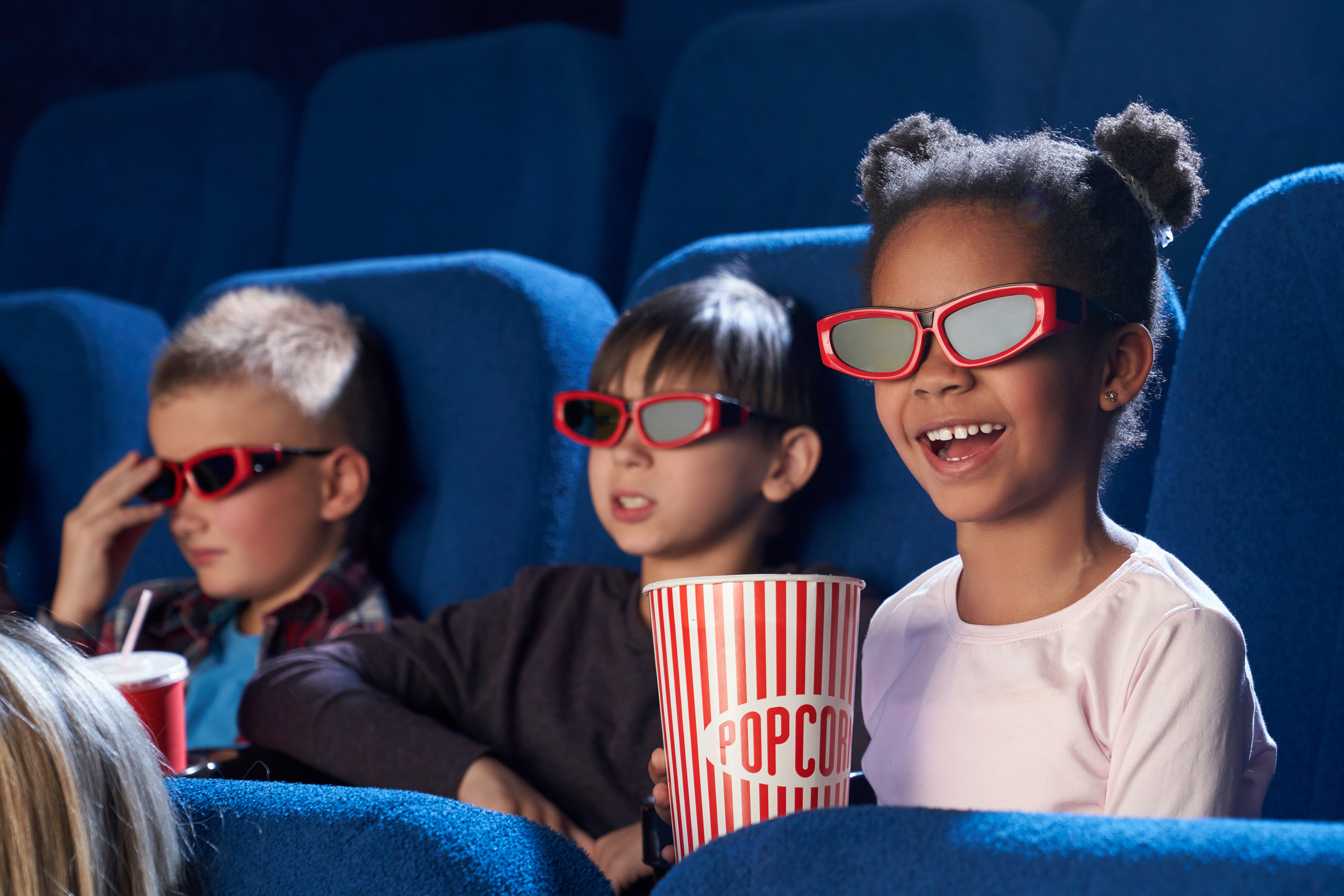 Happy child in 3d glasses watching comical movie in cinema