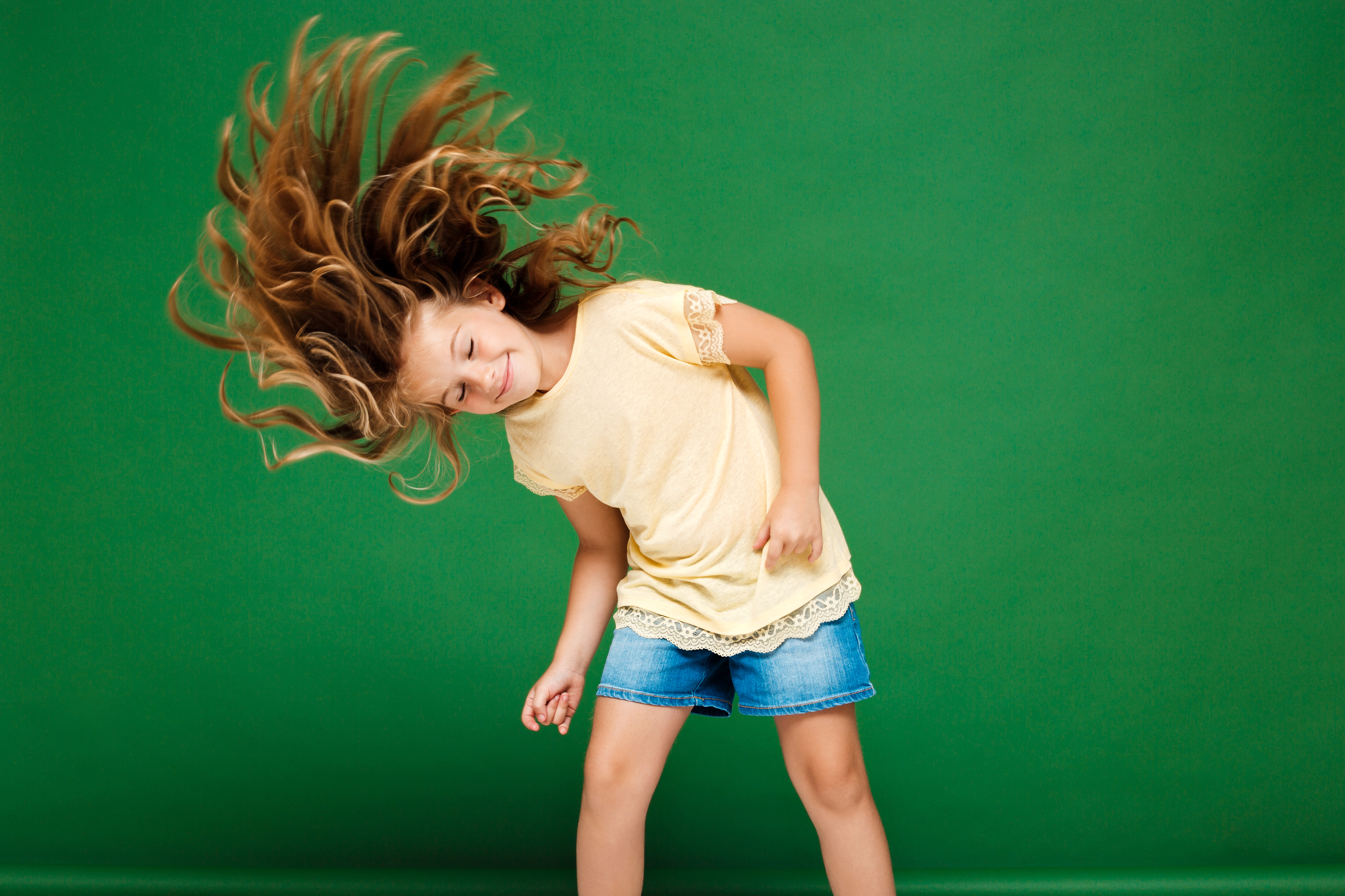 Young pretty girl dancing over green background.