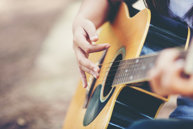 Portrait of beautiful girl playing the guitar with bike at nature background