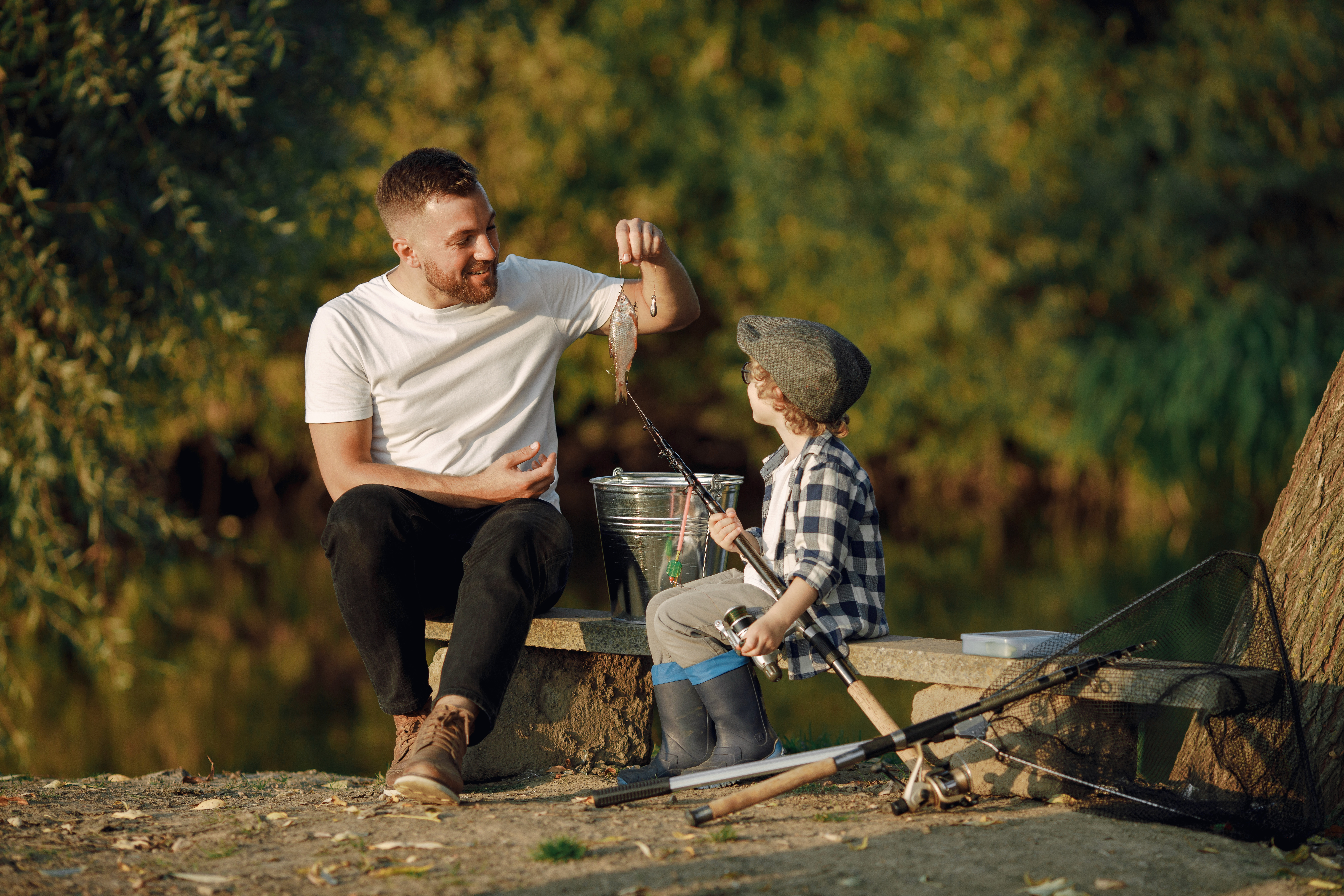 Young father teaching his little toddler son how to fish