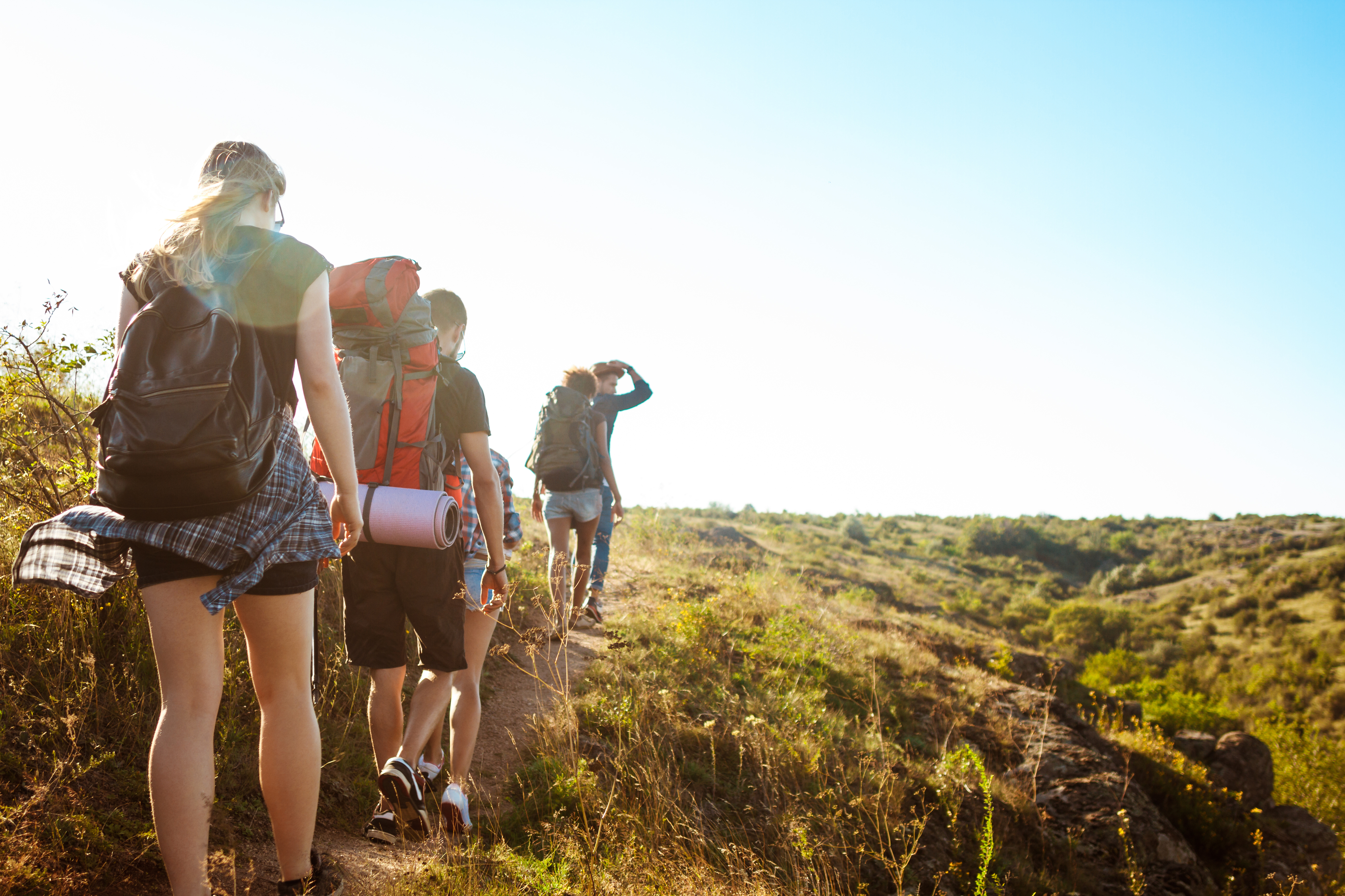 Young beautiful friends travelers with backpacks walking in canyon.